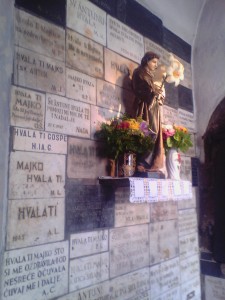 Imagem de Santo Antônio rodeada por várias placas de agradecimento.