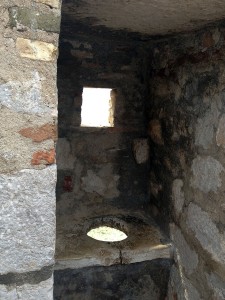 Um nicho no muro de pedra capaz de abrigar uma pessoa sentada. Um buraco redondo na base do nicho atravessa todo o muro, para que as necessidades caiam para fora do muro.