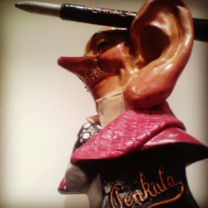 Um busto de Penkala, com seu ouvido esquerdo exageradamente grande segurando uma caneta-tinteiro