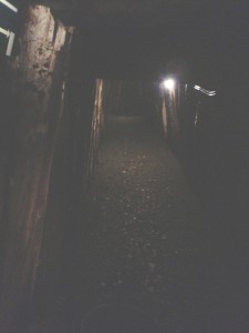 Um túnel escuro da mina, com vigas de madeira sustentando a passagem.